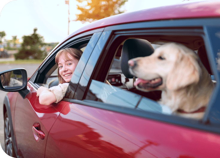 Girl with her dog in a car, happy about having auto insurance in Alberta